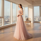 Woman in a pink evening gown standing against a textured gray wall.