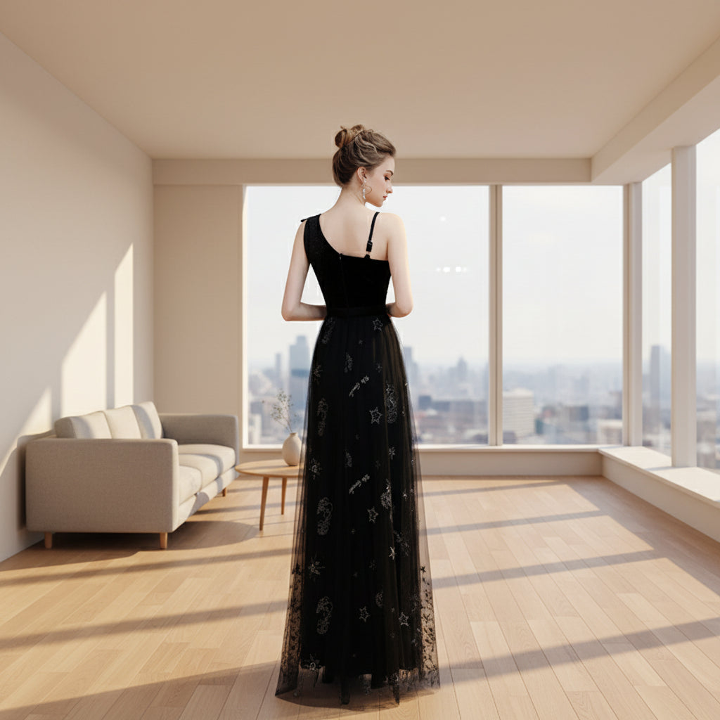 Woman wearing a black evening gown with floral embroidery in an indoor setting.