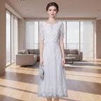 Woman wearing a white lace dress against a gray background