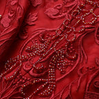 Close-up of red embroidered fabric with intricate patterns and beads