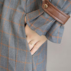 Gray checkered coat with a brown leather pocket on a neutral background