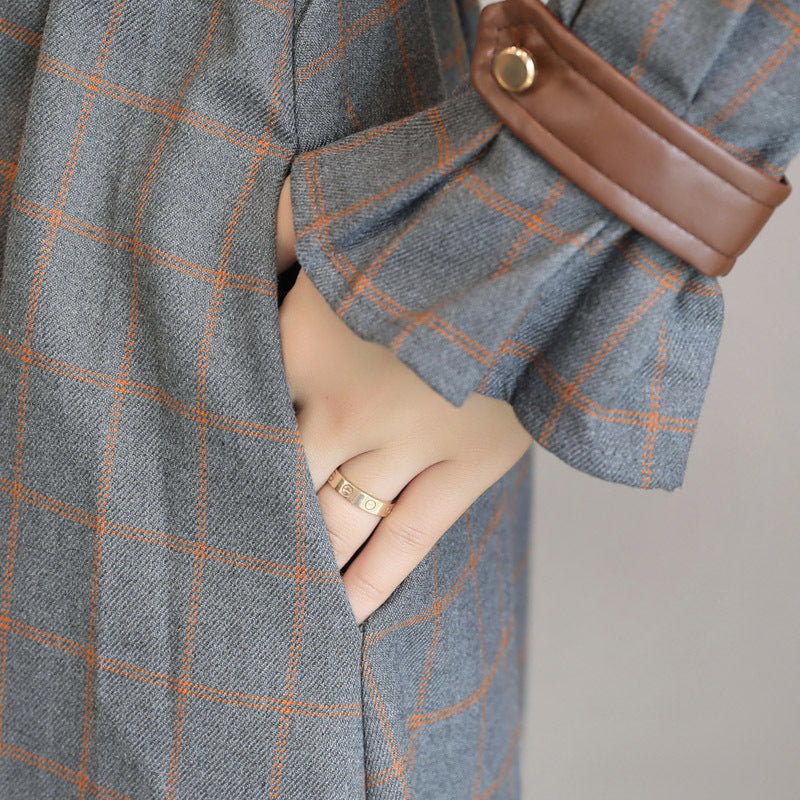 Gray checkered coat with a brown leather pocket on a neutral background