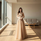 Woman in a beige evening gown with intricate detailing standing indoors.