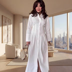 Woman in a long white dress standing in an indoor setting with wooden flooring and a modern interior.